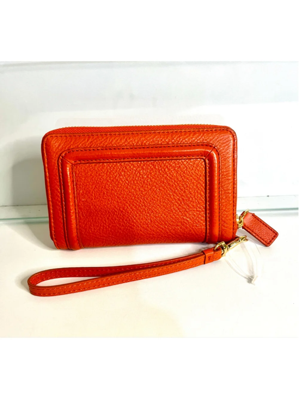 Tory Burch Amanda zip-around wallet featuring vibrant orange pebbled leather.